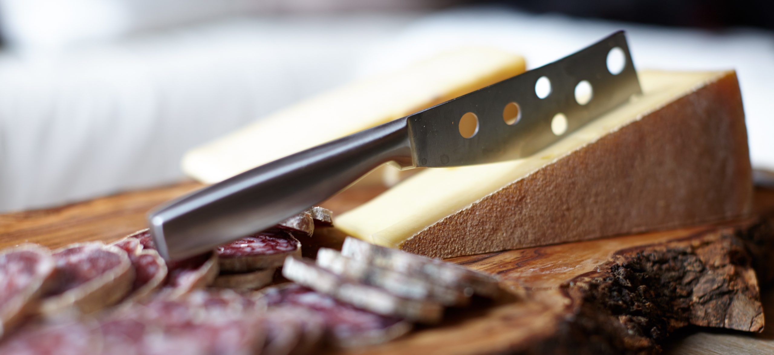 parmesan dairy prices – Copy A block of parmesan on a wooden board. A cheese knife is wedged into the cheese.